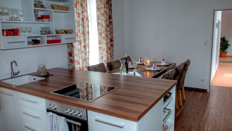 Moderne K&uuml;che mit Esstisch in einem Loft, dekoriert mit Blumenmustervorh&auml;ngen.