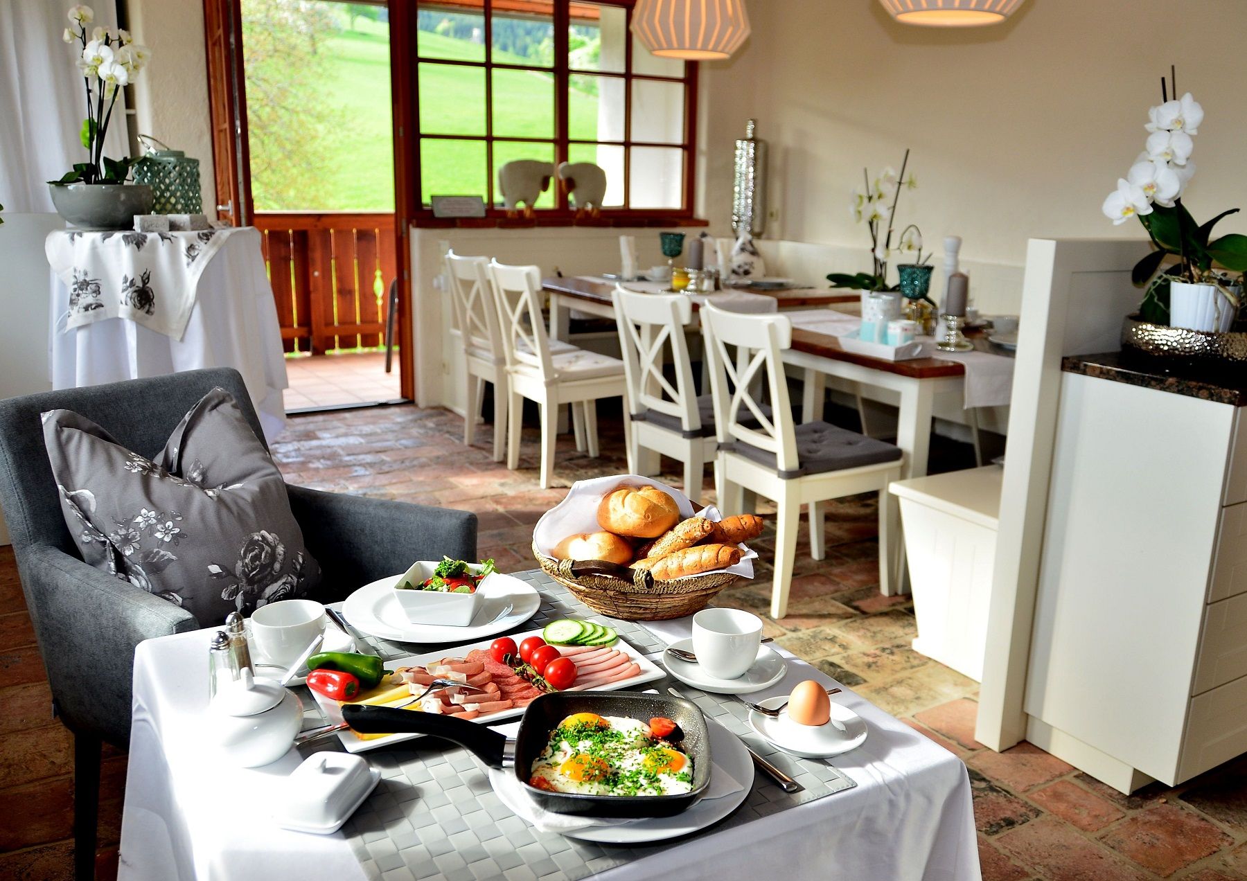 Frühstückstisch in einem gemütlichen Esszimmer mit Blick auf eine grüne Landschaft.