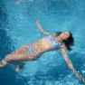 Frau in blauem Bikini treibt entspannt im Pool.