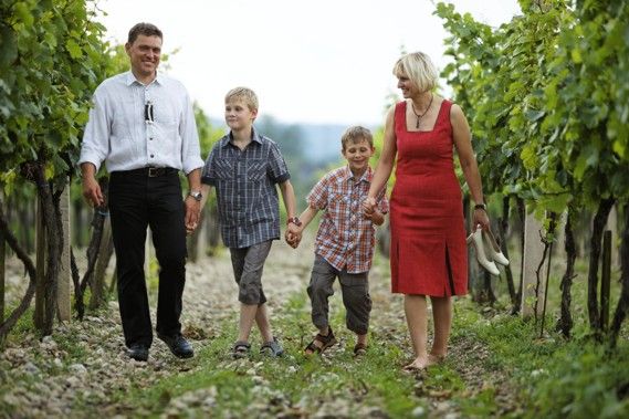 Eine Familie spaziert durch einen Weinberg, bestehend aus einem Mann, einer Frau und zwei Jungen.