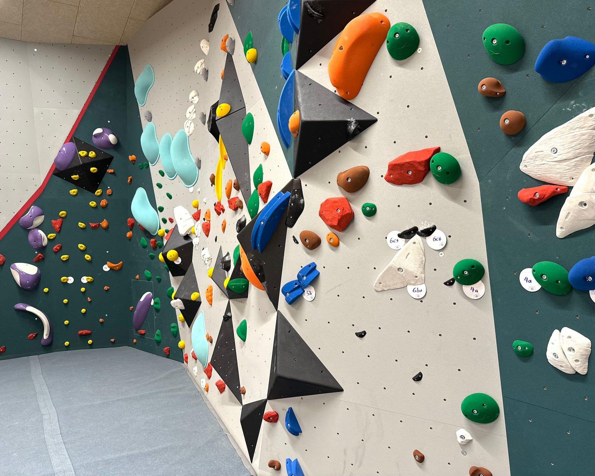 Boulderwand mit bunten Griffen in einer Kletterhalle.