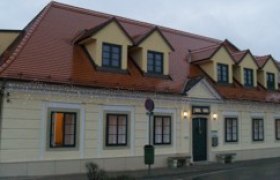 Zweistöckiges Gebäude mit gelber Fassade und rotem Dach.