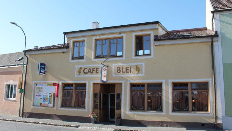Außenansicht des Café Blei mit gelber Fassade und großen Fenstern.