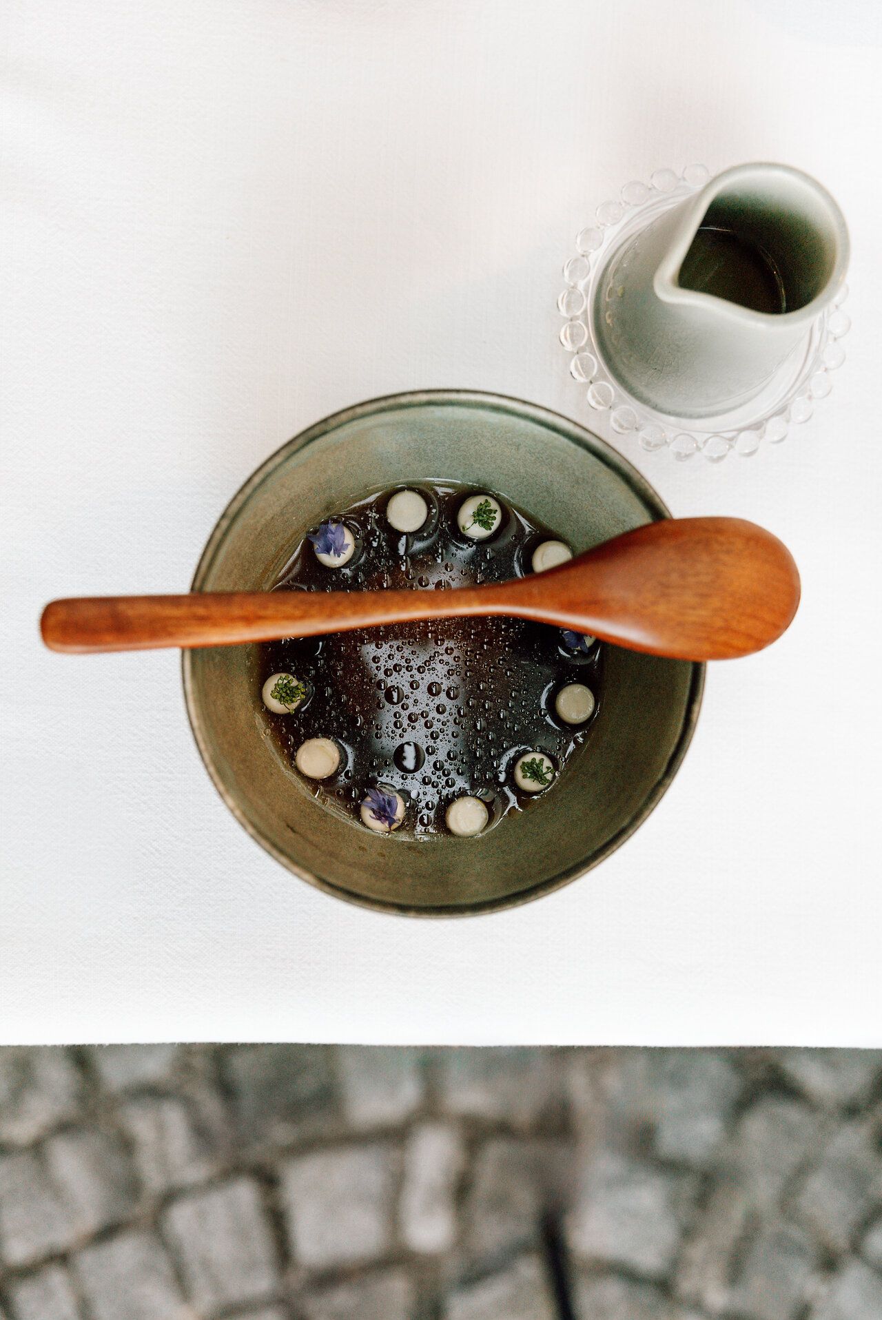 Eine Person sitzt auf einem Hocker in einem schlichten Innenraum und blickt in die Kamera