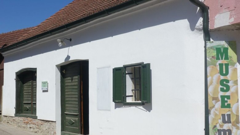 Weißes Gebäude mit grünem Fensterladen und Tür, Schild mit Aufschrift 'MUSEUM'.