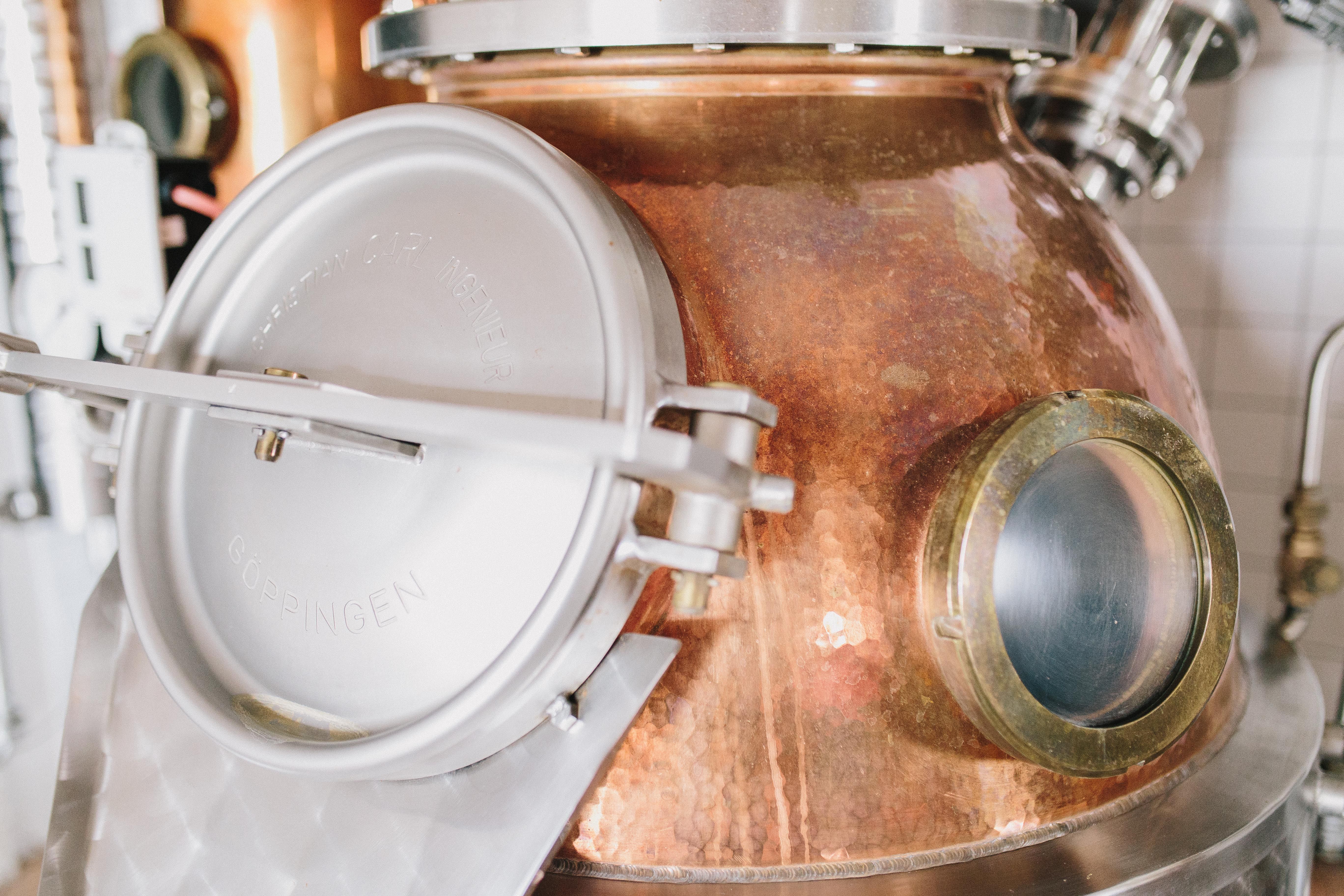 Nahaufnahme einer Kupferdestille mit Metallverschluss und Sichtfenster.