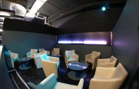 Lounge-Bereich mit beigen Sesseln und runden Tischen in einem modernen Raum.