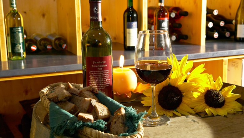 Weinflasche und Glas auf einem Fass mit Brot und Sonnenblumen.