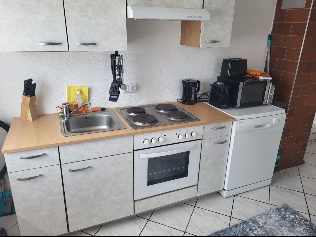 Küchenzeile mit Herd, Spüle, Mikrowelle und Geschirrspüler.