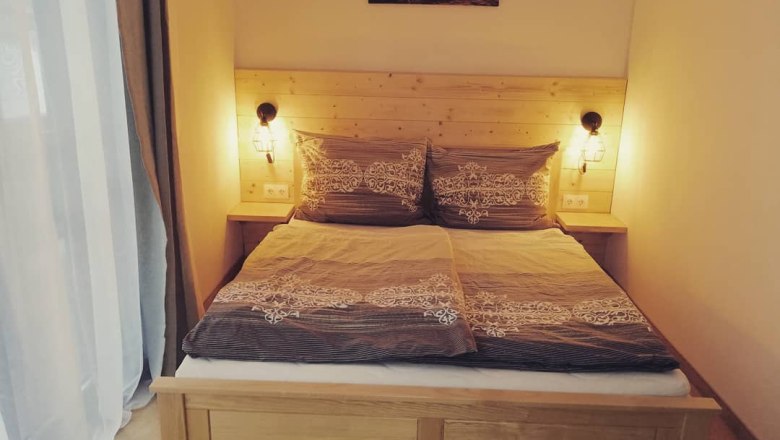 Gemütliches Doppelzimmer mit Holzbett und Nachttischlampen.