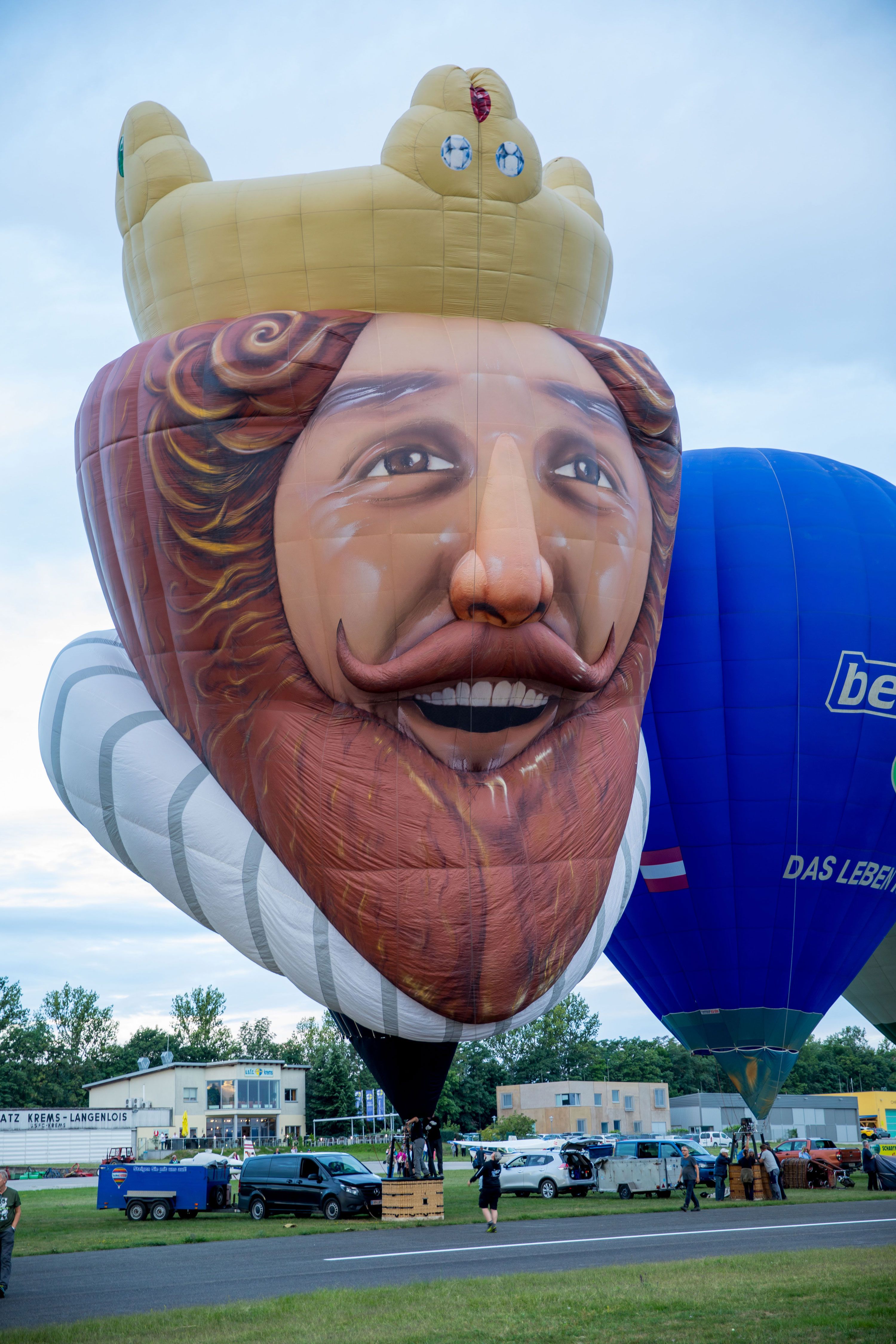 Heißluftballon in Form eines lächelnden Königs mit Krone bei einem Ballonfestival.