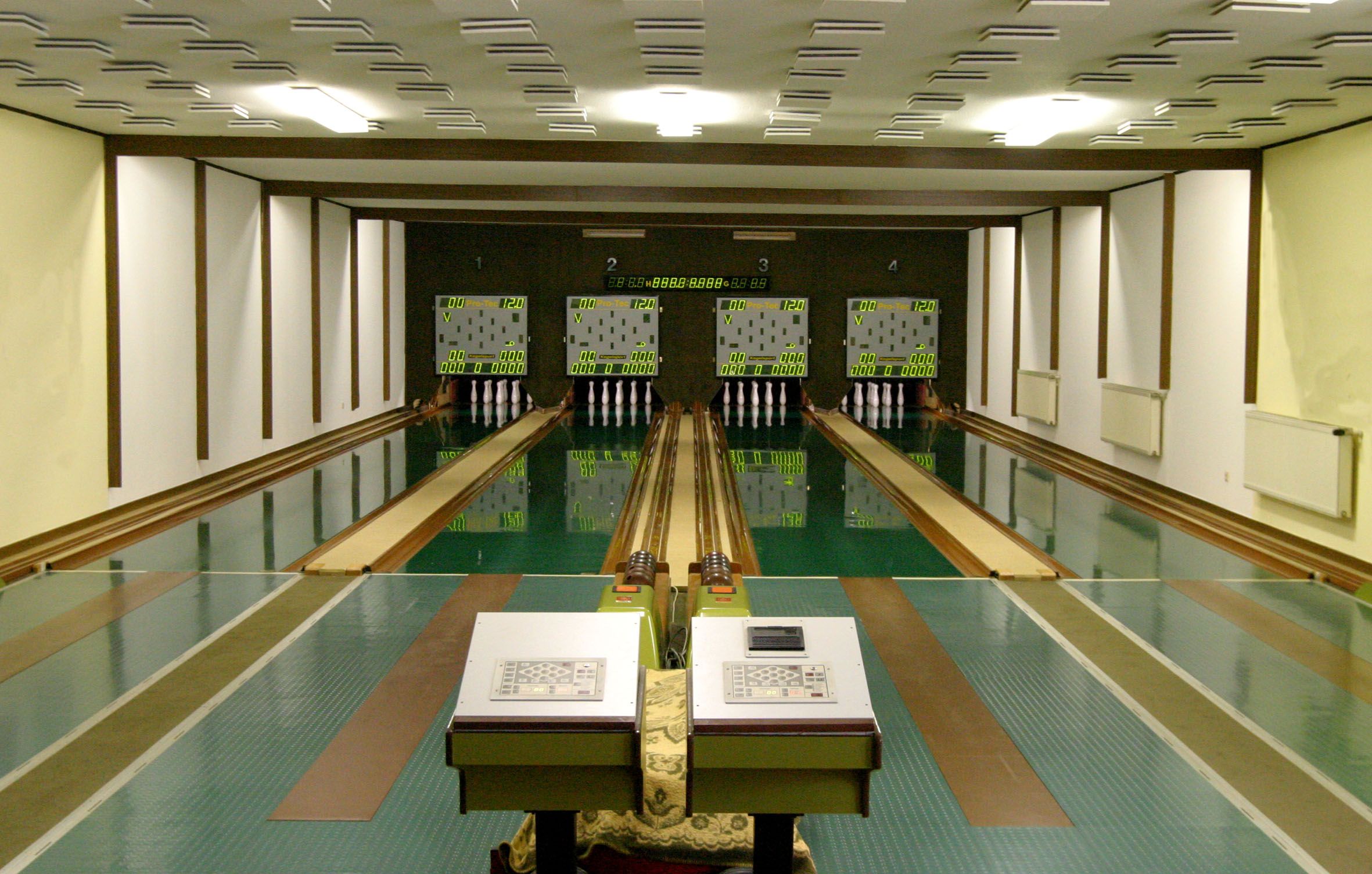 Innenansicht einer Kegelbahn mit vier Bahnen und Anzeigetafeln.