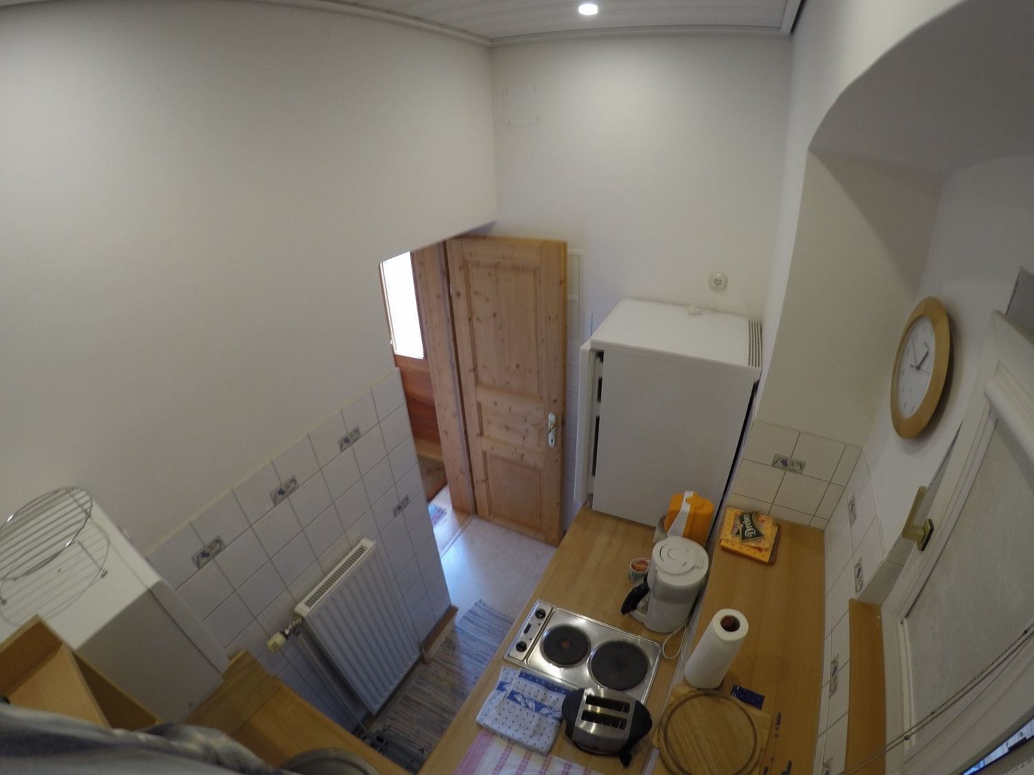 Kleine Küche mit Herd, Kühlschrank und Holztür.