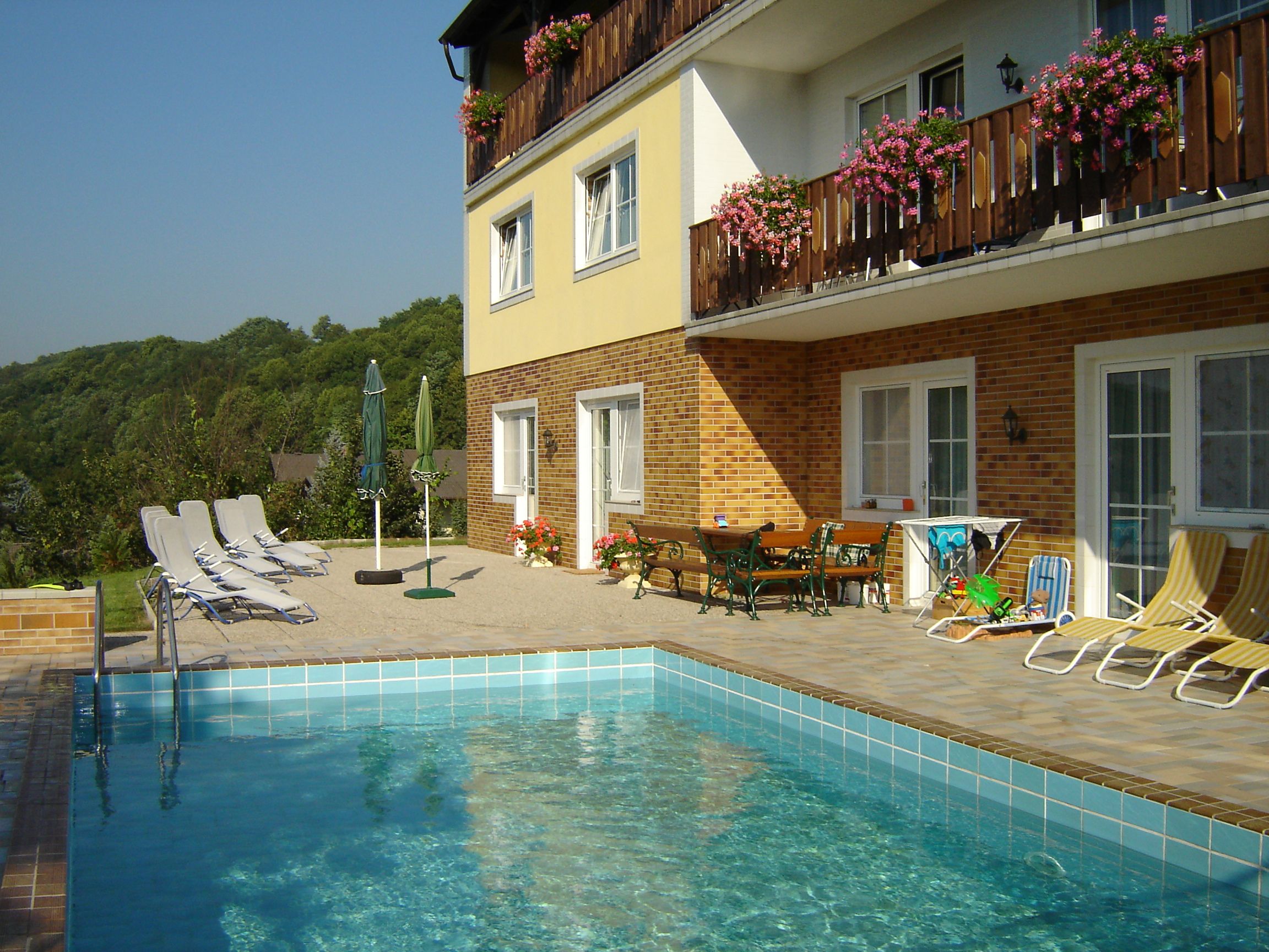 Außenansicht einer Pension mit Pool und Liegestühlen.