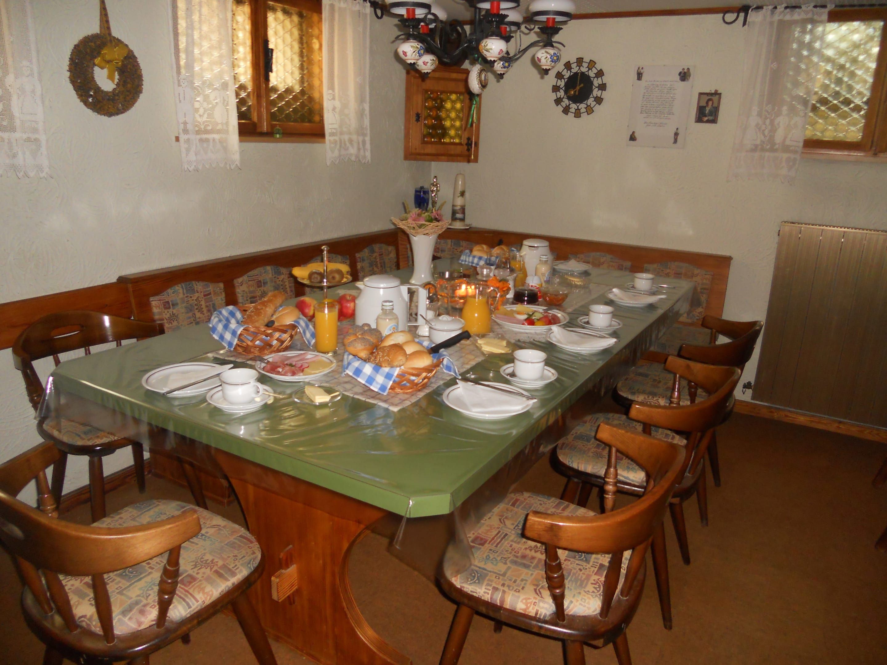 Frühstücksraum mit einem Tisch und Stühlen. Am Tisch ist ein umfangreiches Frühstück aufgedeckt.