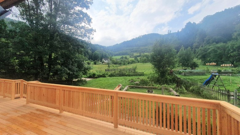 Blick von einer Terrasse auf eine grüne Landschaft mit Bäumen und Hügeln.
