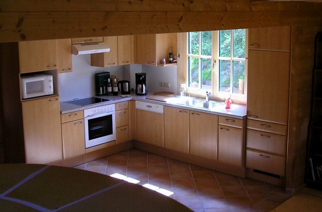 Moderne Küche mit Holzschränken, Herd, Spüle und Fenster.