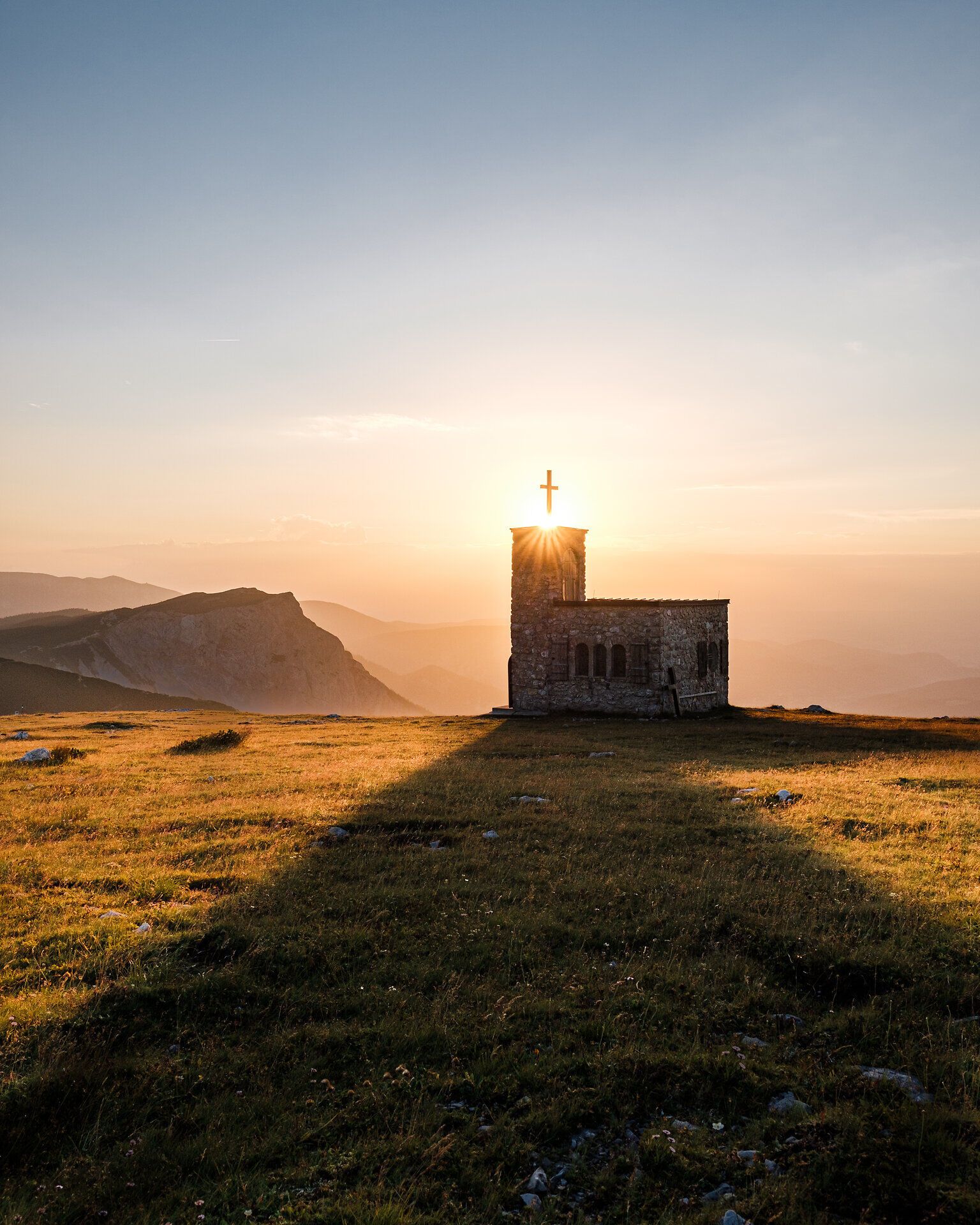 Die sanften Hügel der Wiener Alpen umarmen die kleine, charmante Kapelle, die im goldenen Licht der untergehenden Sonne erstrahlt. Ihre silhouette hebt sich majestätisch gegen den Himmel ab und lädt Wanderer ein, einen Moment der Stille und Besinnung zu genießen. Hier, wo die Natur und die Spiritualität harmonisch verschmelzen, wird jeder Besuch zu einem unvergesslichen Erlebnis.