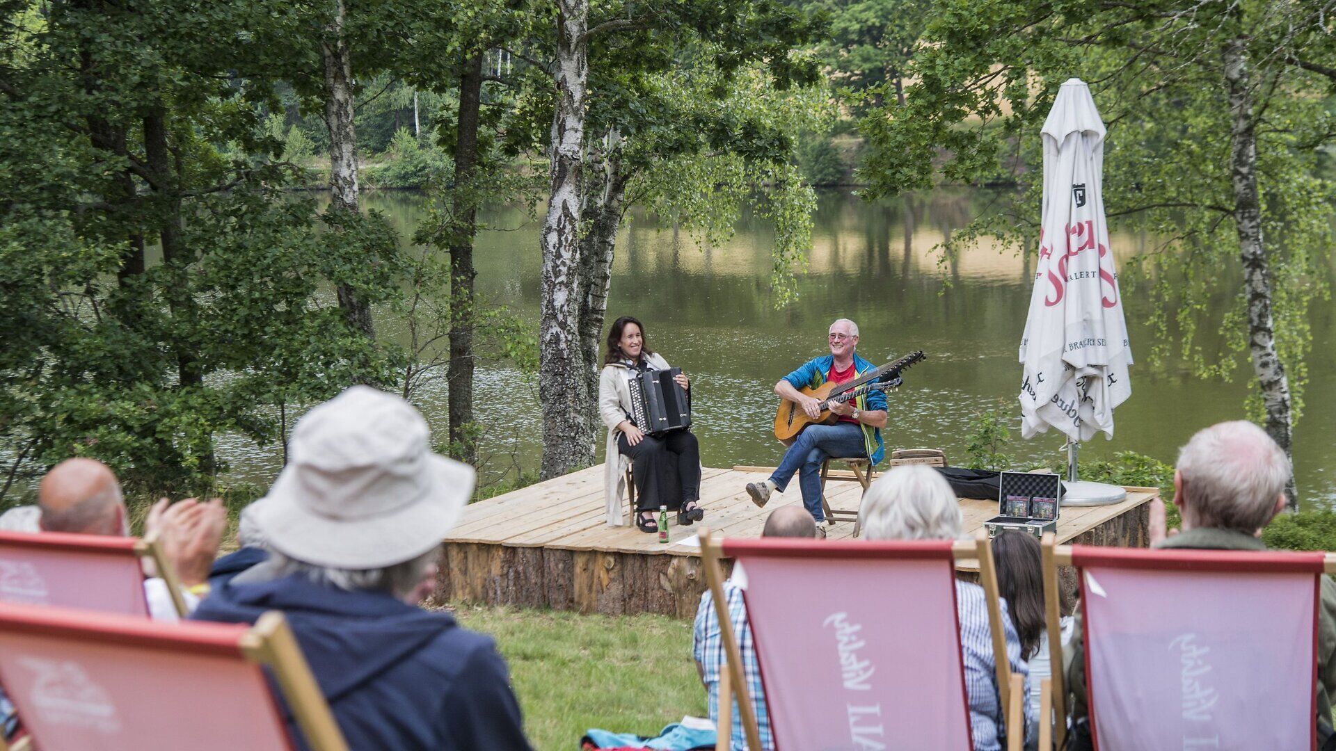 Inmitten der idyllischen Natur des Waldviertels entfaltet sich beim Schrammel.Klang.Festival in Litschau eine harmonische Melodie, während zwei talentierte Musiker mit Leidenschaft ihre Instrumente spielen. Die sanften Klänge der Gitarre und des Akkordeons laden die Zuhörer ein, den Moment zu genießen und die Seele baumeln zu lassen.