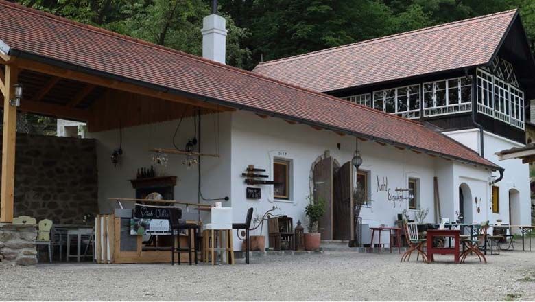 Ein traditionelles Gebäude mit rotem Ziegeldach und Holzelementen, umgeben von Bäumen.