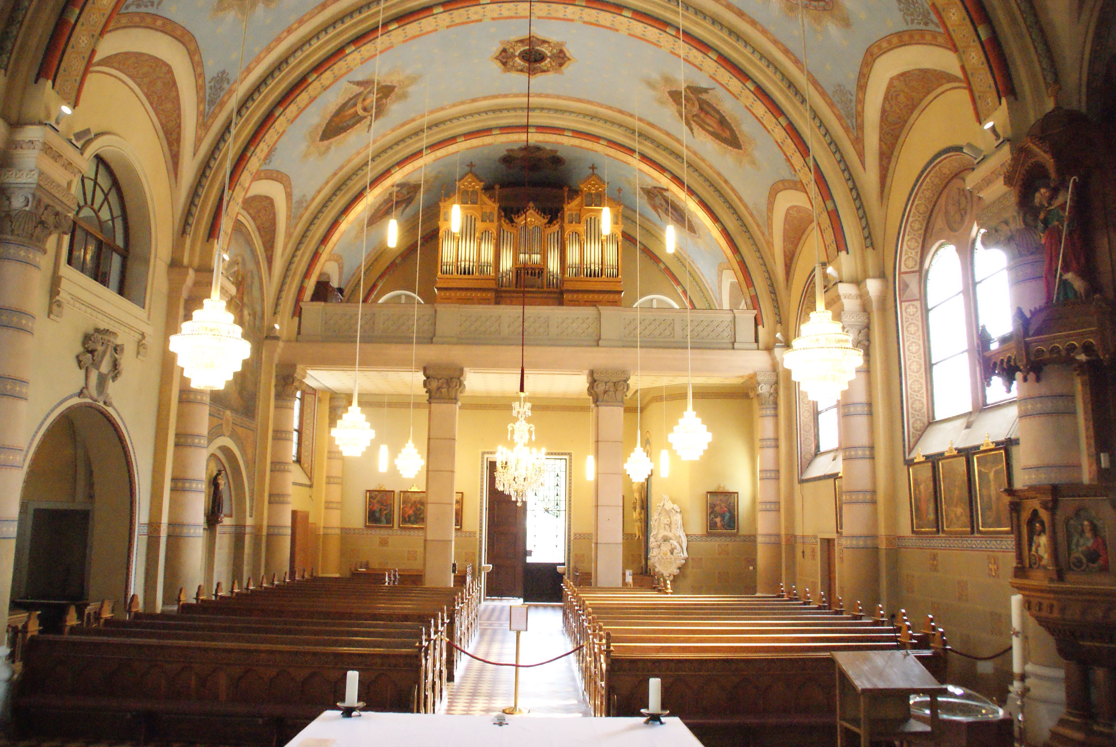 Innenansicht der Pfarrkirche zum Hl. Martin mit Bänken, Orgel und Kronleuchtern.