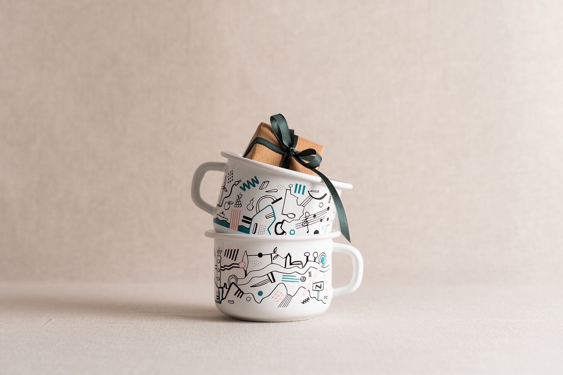 Niederösterreich-Tasse 2026 designt von Andi Fränzl gestapelt mit einem Päckchen in der obersten Tasse. 