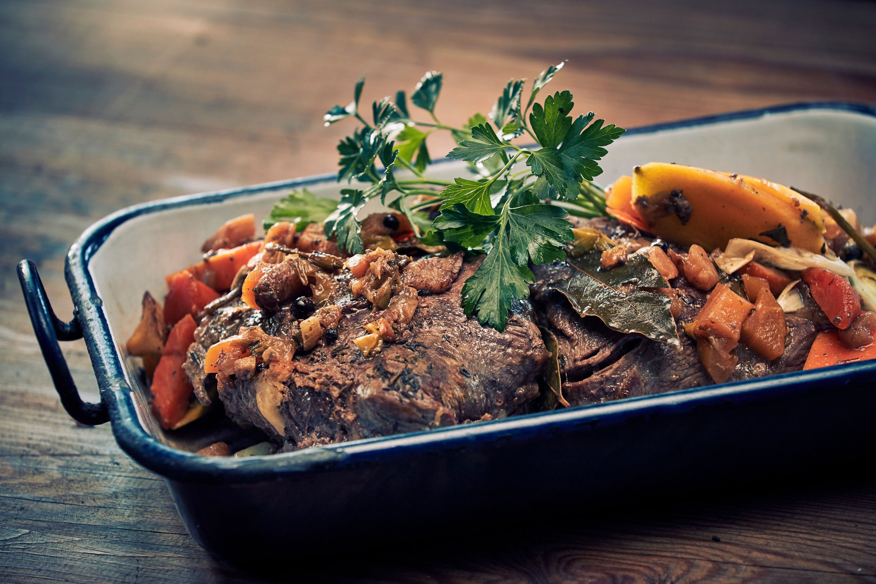 Ein Braten mit Gemüse und Kräutern in einer Auflaufform.