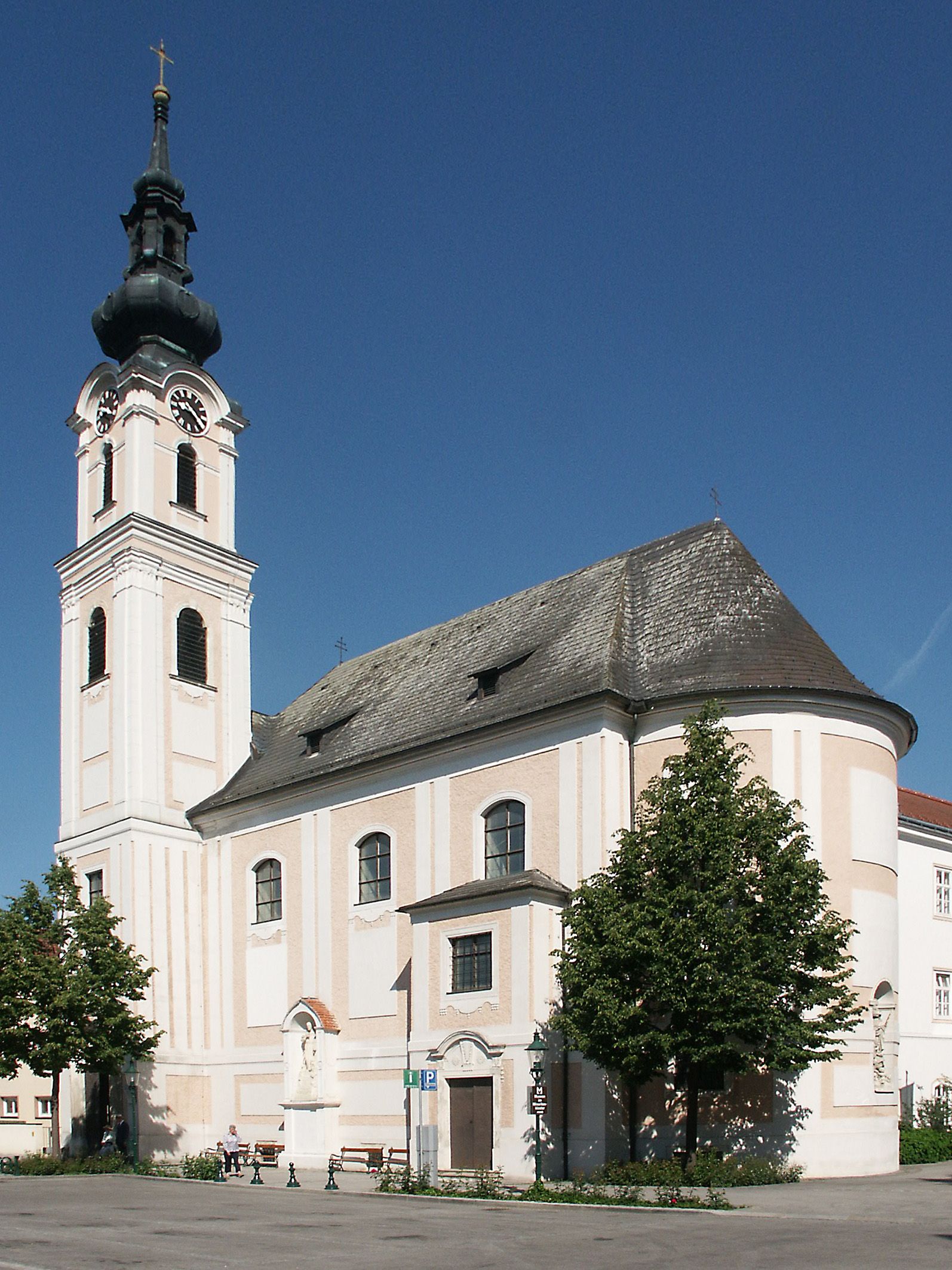 Die Minoritenkirche in Tulln mit ihrem markanten Turm und barocker Architektur vor blauem Himmel.