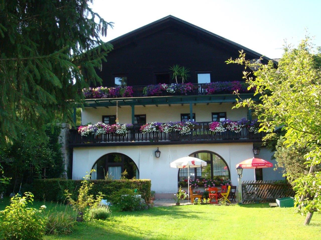 Ein traditionelles Gasthaus mit Holzbalkon und Blumen in Scheibbs, umgeben von einem grünen Garten.