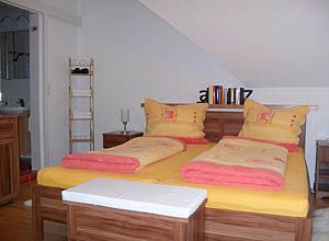 Gemütliches Schlafzimmer mit Doppelbett und gelb-roter Bettwäsche.