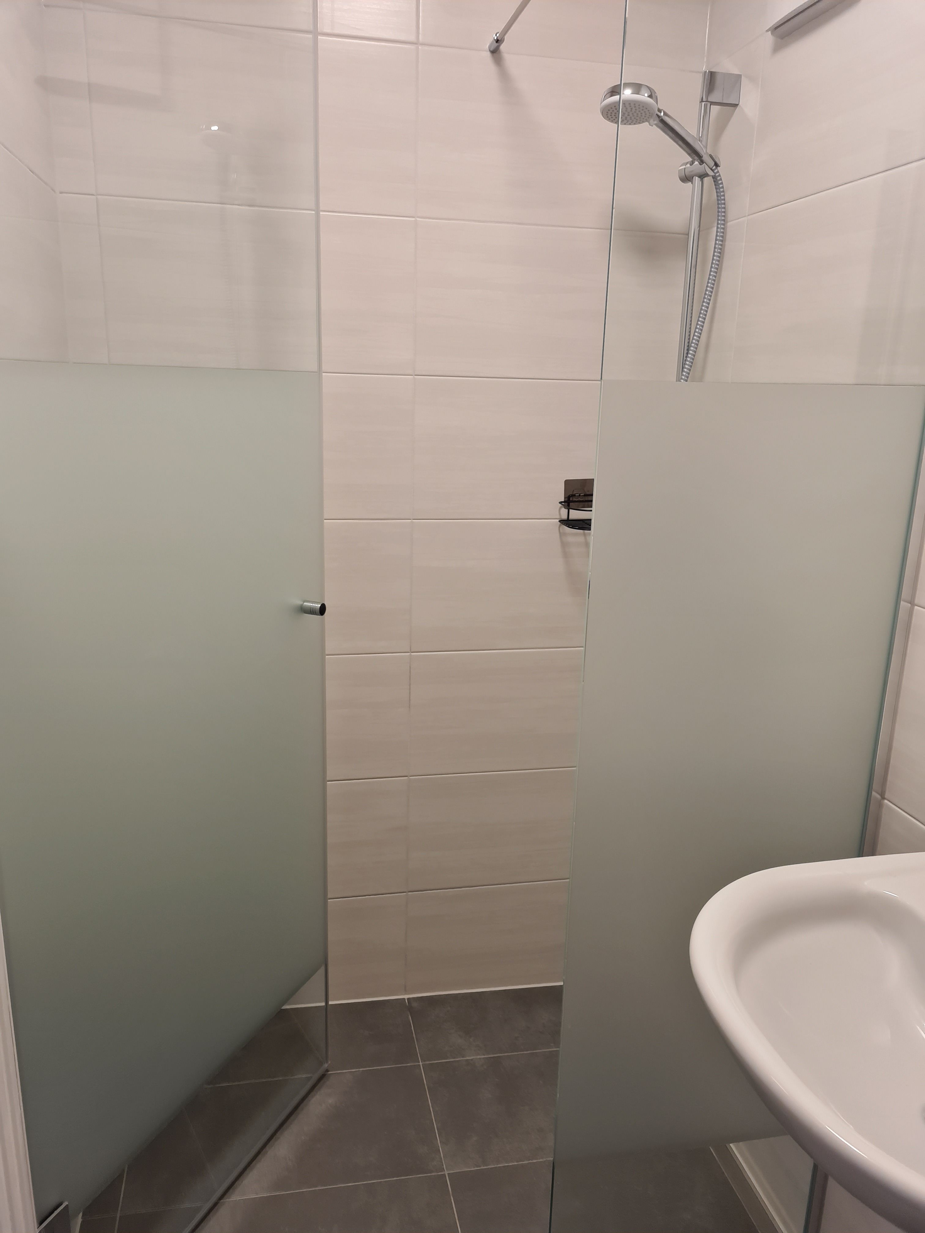 Moderne Dusche mit Glaswänden und Duschkopf in einem Badezimmer.