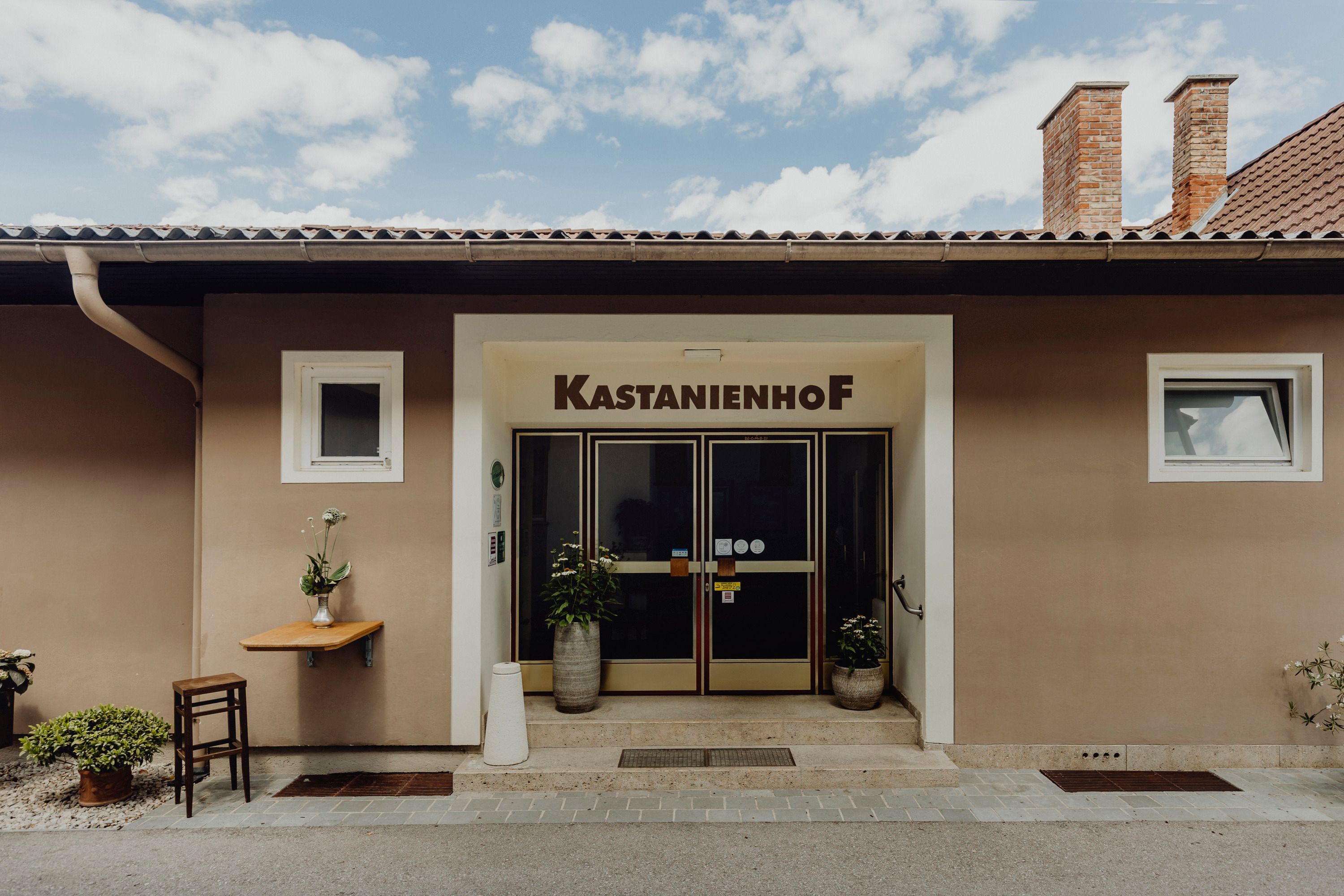 Eingang des Kastanienhofs in Grafenbach mit Pflanzen und Tisch.