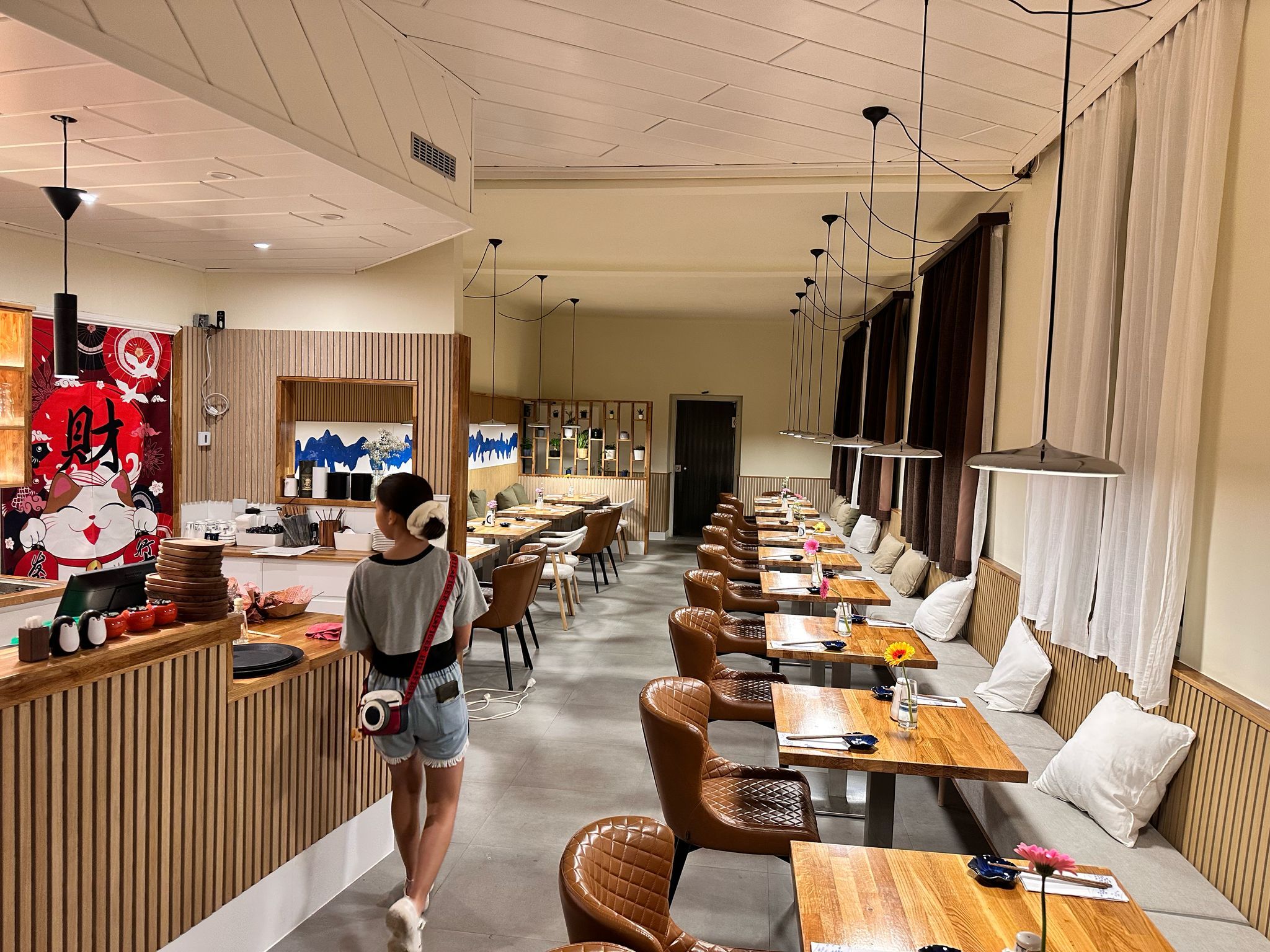 Innenansicht eines modernen Restaurants mit Holztischen und Ledersesseln.