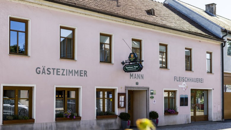 Gasthaus mit G&auml;stezimmern in rosa Geb&auml;ude.