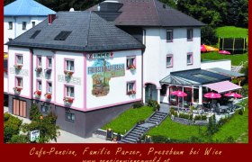 Außenansicht der Cafe-Pension Parzer mit Terrasse und Sonnenschirmen.