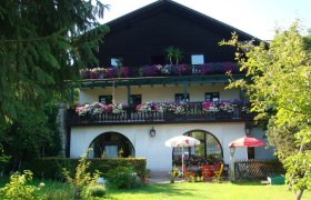 Ein traditionelles Gasthaus mit Holzbalkon und Blumen in Scheibbs, umgeben von einem grünen Garten.