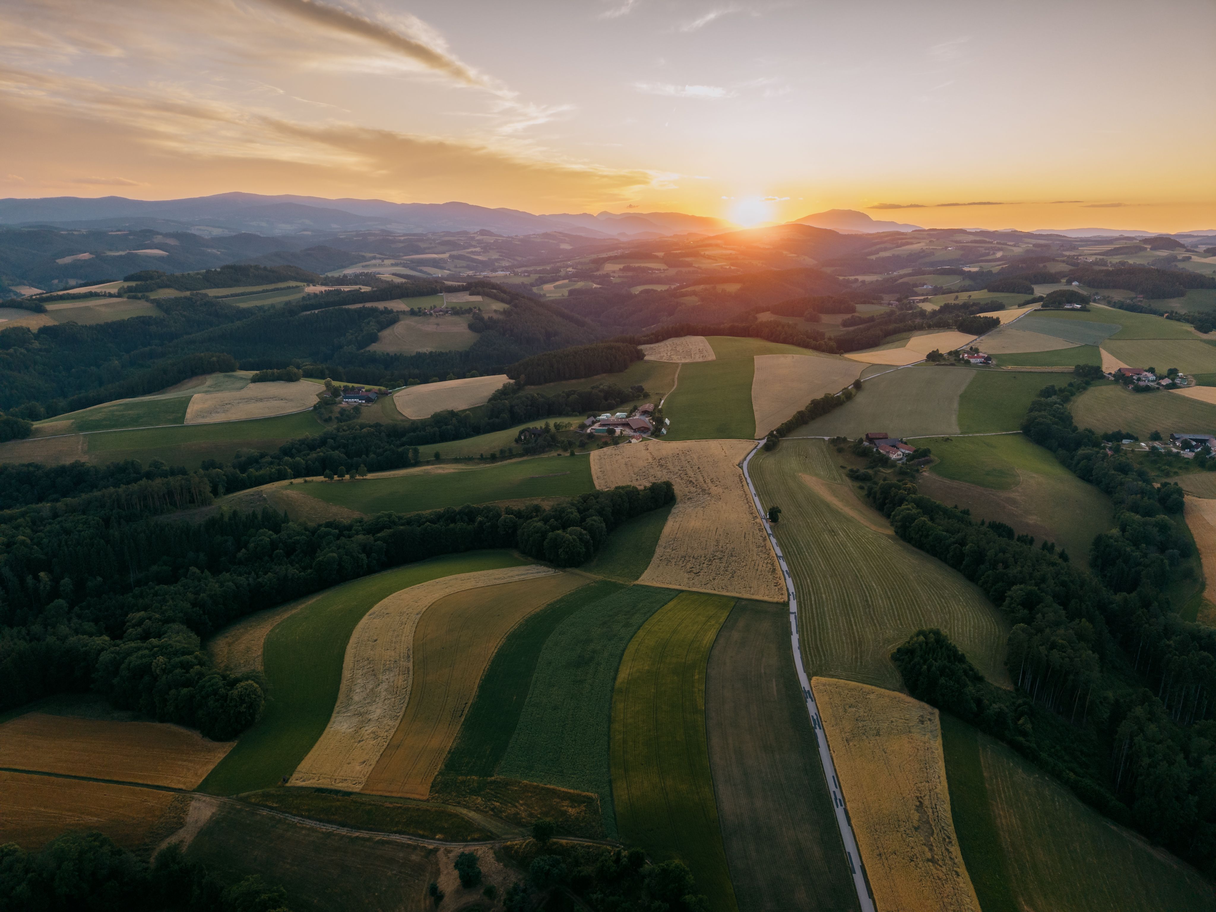 Luftaufnahme einer hügeligen Landschaft bei Sonnenuntergang