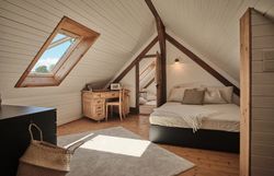 Rustikales Steinhaus mit Holztür, Bank und Blumen im Vordergrund.