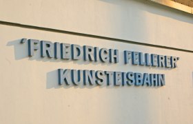 Schriftzug 'Friedrich Fellerer Kunsteisbahn' an einer Wand.