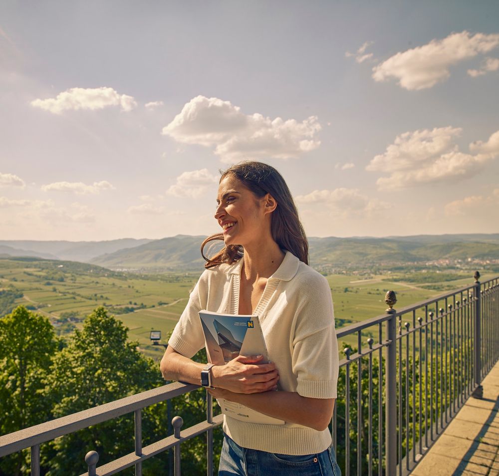 Seminarteilnehmerin steht beim Geländer der Terrasse und genießt die Aussicht in die Wachau.
