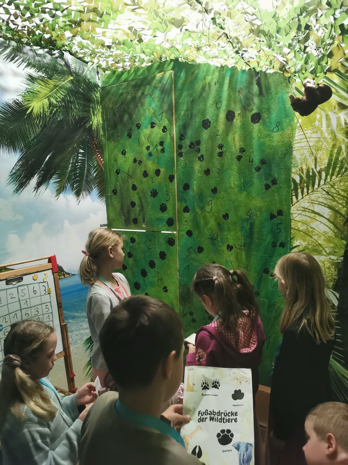 Kinder stehen im Raum und lesen ein Rätsel 