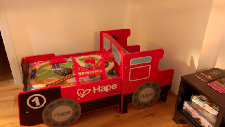 Rotes Spielzeugbett in Form einer Lokomotive mit Spielzeugeisenbahn.