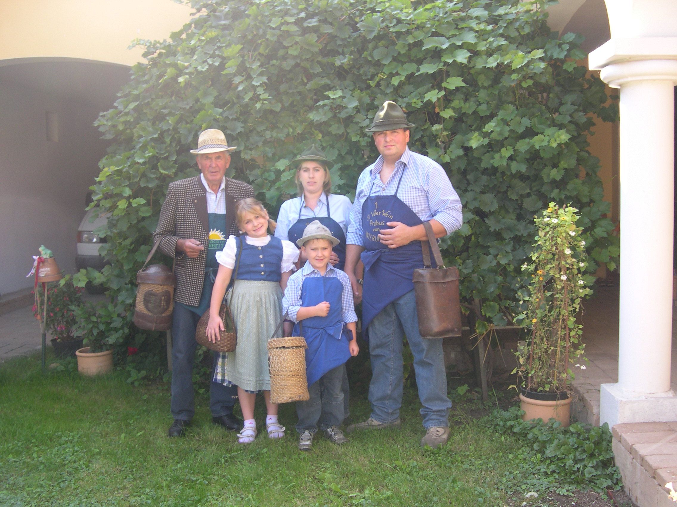 Familie in traditioneller Kleidung vor einem Weinstock.