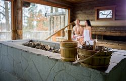 Modernes Hotelzimmer mit Doppelbett, Naturbild an der Wand, Sessel, Tisch und Stehlampe.