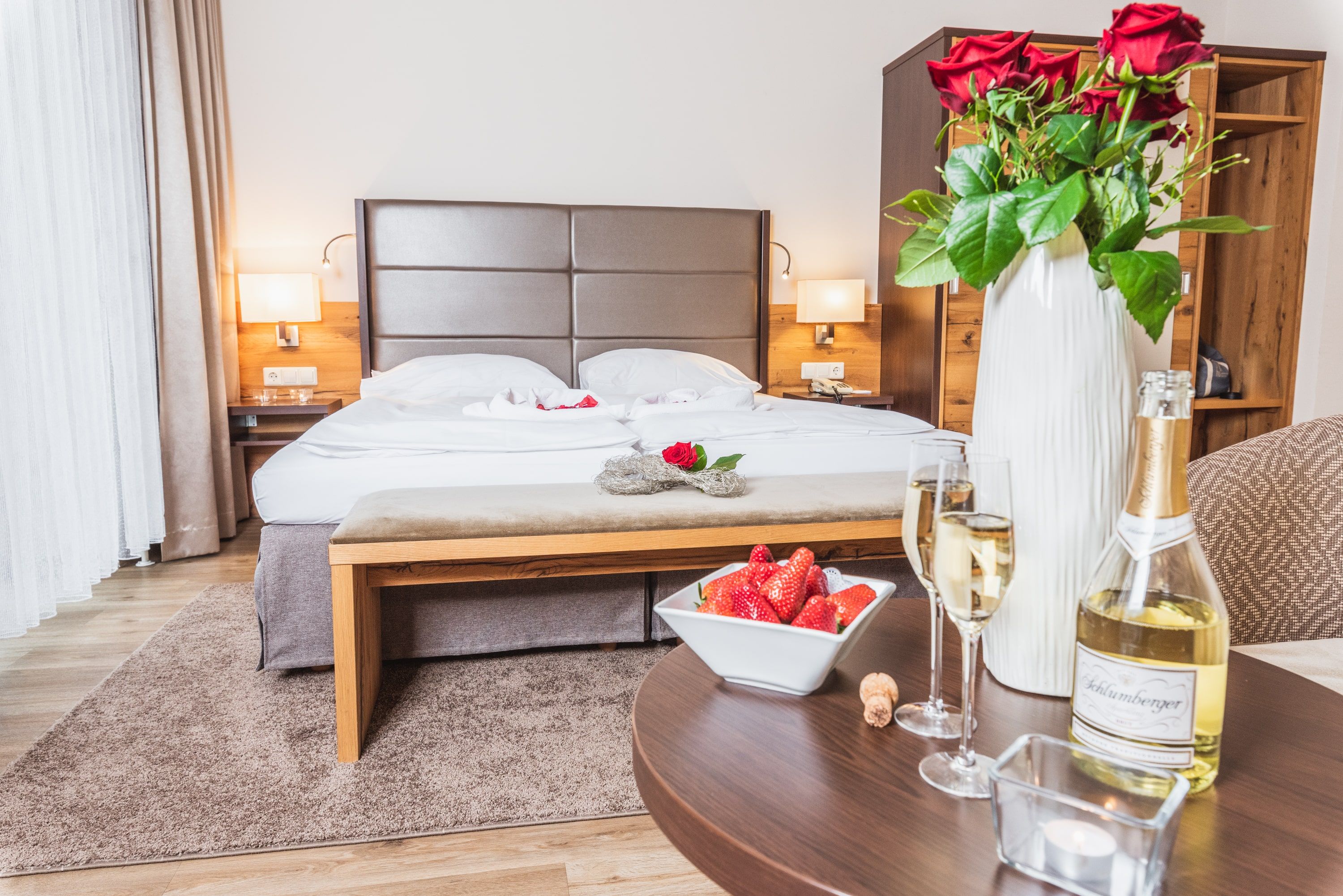 Doppelzimmer im Hotel Schneeberghof mit Bett, Rosen, Sekt und Erdbeeren.