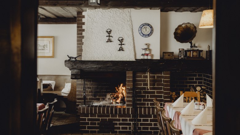 Gem&uuml;tliches Restaurant mit Kamin, rustikaler Einrichtung und gedecktem Tisch.