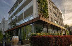 Ein stilvoll eingerichtetes Hotelzimmer mit einem großen roten Schuh als Bücherregal, antiken Stühlen, einem Tisch und einer Stehlampe.