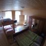 Holzvert&auml;feltes Schlafzimmer mit Etagenbett, Doppelbett, Kleiderschrank und Fernseher.