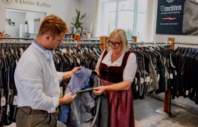 Zwei Personen betrachten ein Trachtenkleidungsstück in einem Bekleidungsgeschäft.