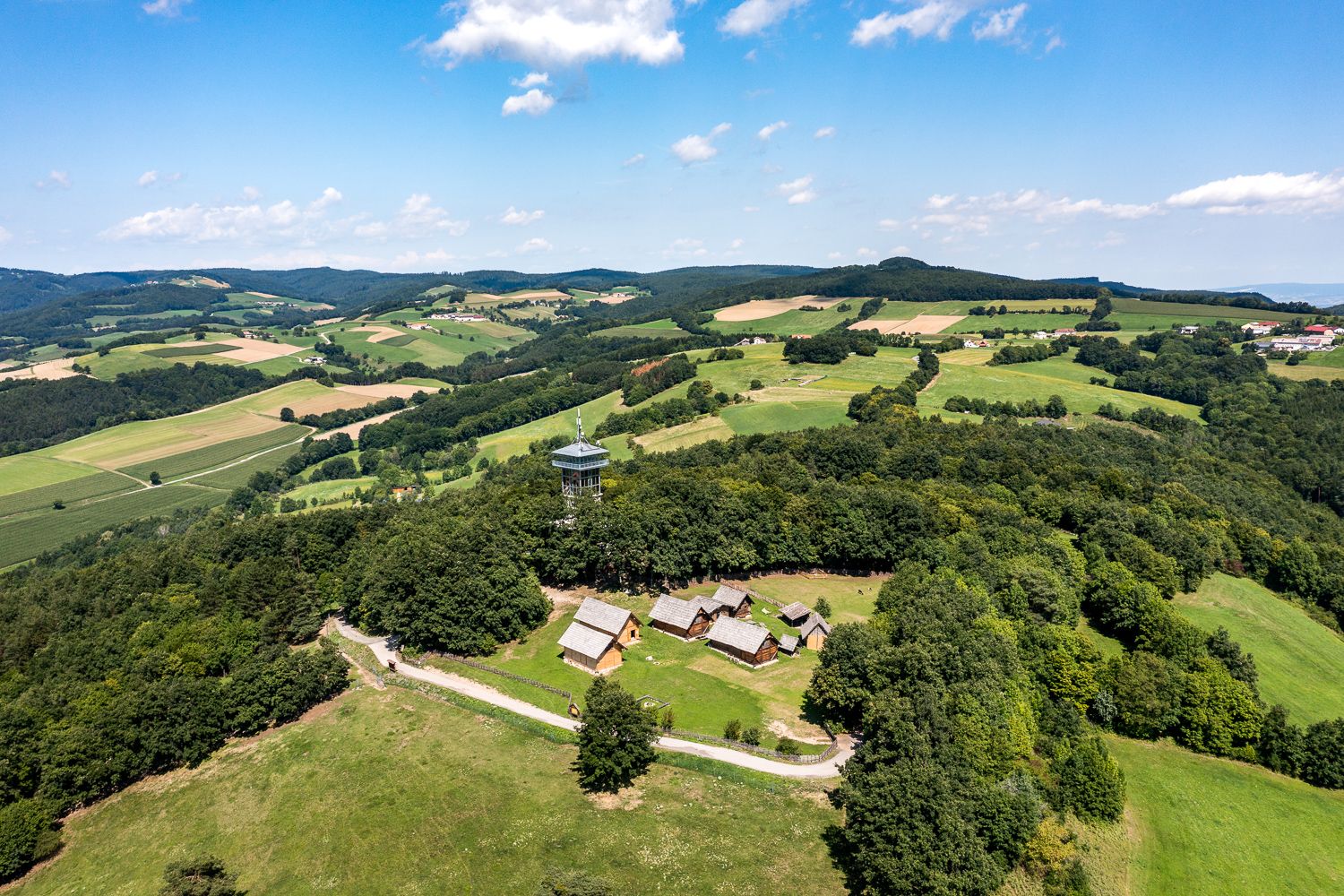 Luftaufnahme des Keltendorfs Schwarzenbach mit Aussichtsturm inmitten grüner Landschaft.
